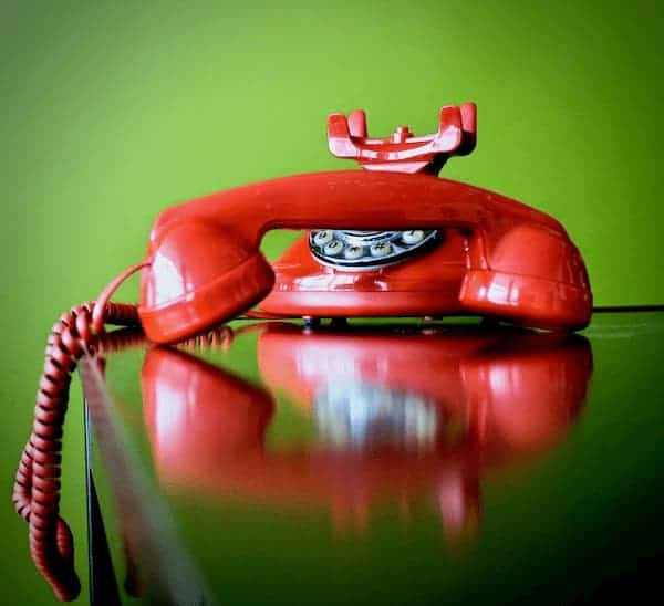 Teléfono convencional rojo puesto sobre un escritorio, con su auricular descolgado. ¿Cuál es la diferencia de la telefonía IP?.